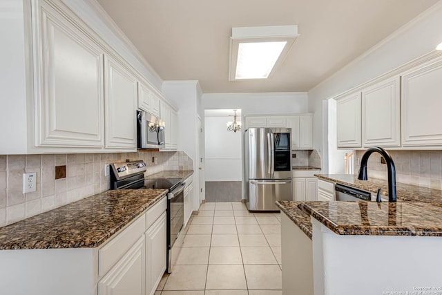 kitchen with white cabinets, light tile patterned floors, stainless steel appliances, and dark stone countertops