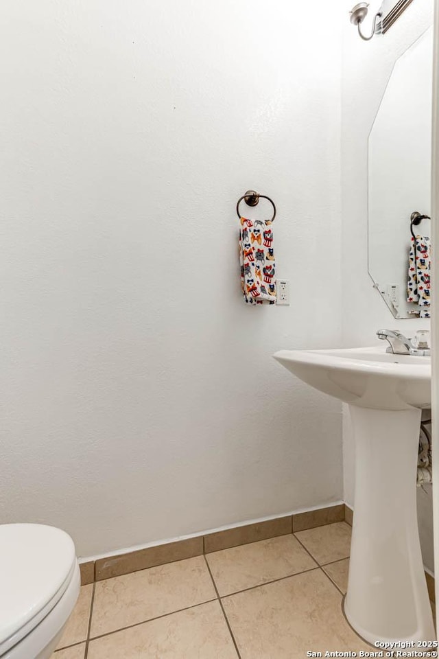 bathroom featuring toilet, tile patterned flooring, and baseboards