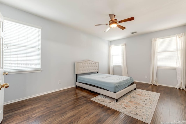 bedroom with a ceiling fan, visible vents, baseboards, and wood finished floors