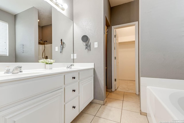 full bathroom featuring a sink, tile patterned floors, a tub, double vanity, and a walk in closet