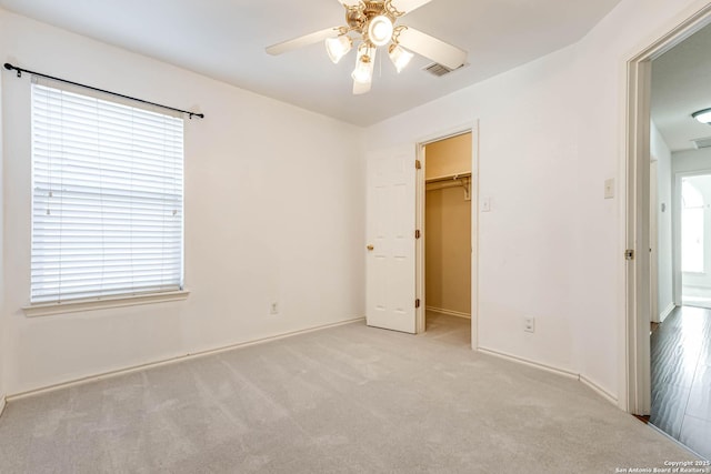 unfurnished bedroom featuring carpet, a closet, visible vents, a spacious closet, and ceiling fan