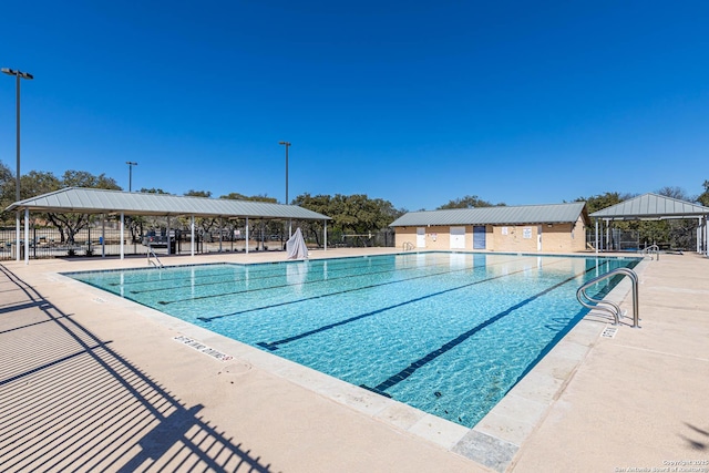 community pool with a patio area, fence, and a gazebo