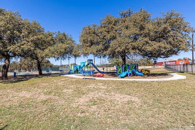 community play area featuring a yard and fence