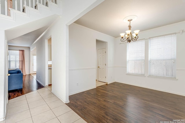 interior space featuring baseboards, a chandelier, crown molding, and wood finished floors