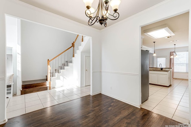 unfurnished room featuring crown molding, stairway, an inviting chandelier, light wood-style floors, and a sink