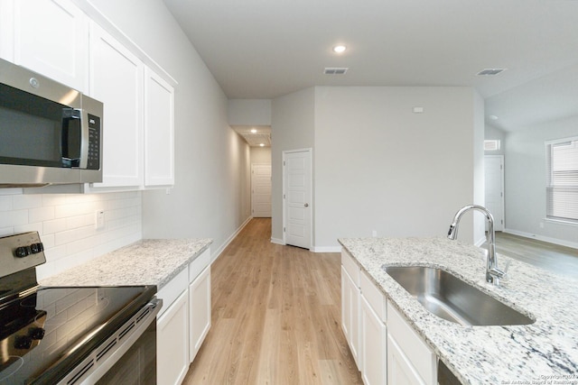 kitchen with white cabinetry, decorative backsplash, stainless steel appliances, and a sink