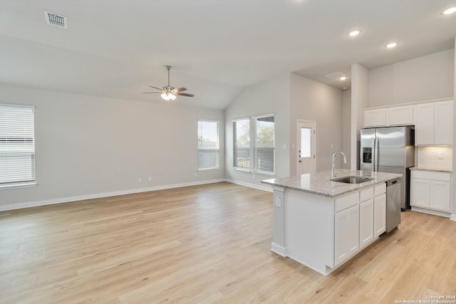 kitchen with a center island with sink, visible vents, stainless steel appliances, white cabinetry, and a sink