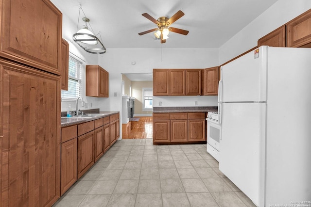 kitchen with white appliances, a ceiling fan, brown cabinetry, and a sink