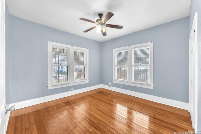 empty room featuring wood-type flooring, a ceiling fan, and baseboards