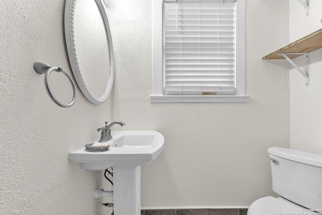 half bath with toilet and a textured wall