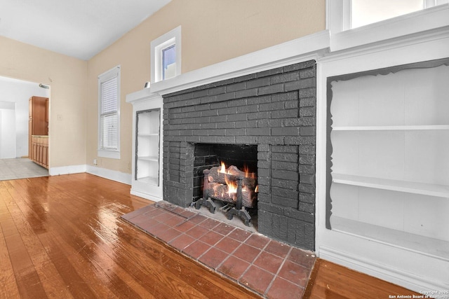 room details featuring a fireplace, baseboards, and wood finished floors