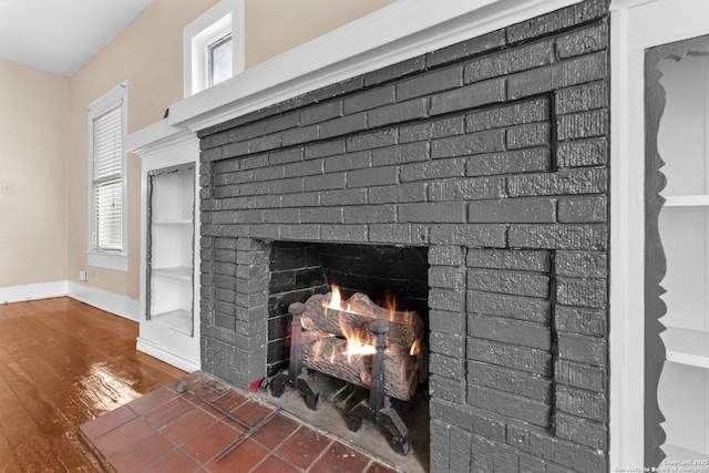 details featuring a brick fireplace, wood finished floors, and baseboards