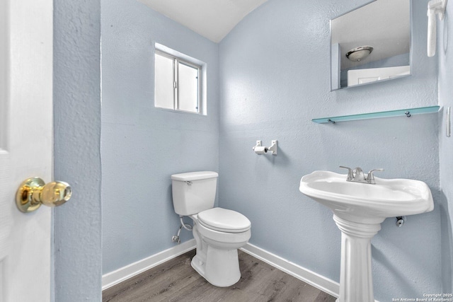 half bathroom with baseboards, a sink, toilet, and wood finished floors