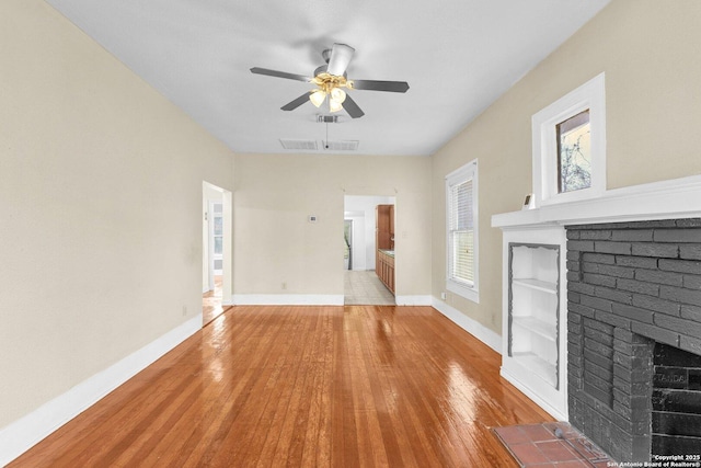 unfurnished living room featuring baseboards, visible vents, ceiling fan, hardwood / wood-style floors, and a fireplace