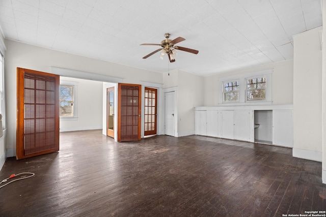 unfurnished living room featuring a healthy amount of sunlight, ceiling fan, baseboards, and wood finished floors