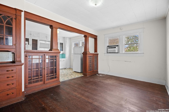 spare room featuring dark wood-style flooring, cooling unit, and baseboards