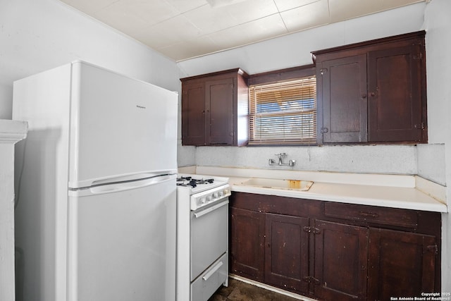 kitchen with light countertops, white appliances, a sink, and dark brown cabinetry