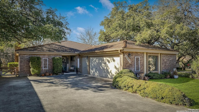 ranch-style house with a garage, a front yard, concrete driveway, and brick siding