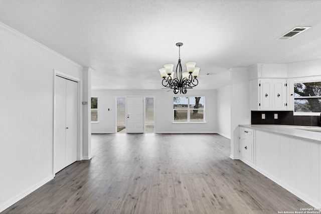 unfurnished living room with a healthy amount of sunlight, visible vents, and wood finished floors