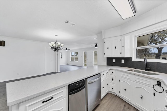 kitchen featuring dishwasher, a peninsula, a sink, white cabinetry, and backsplash