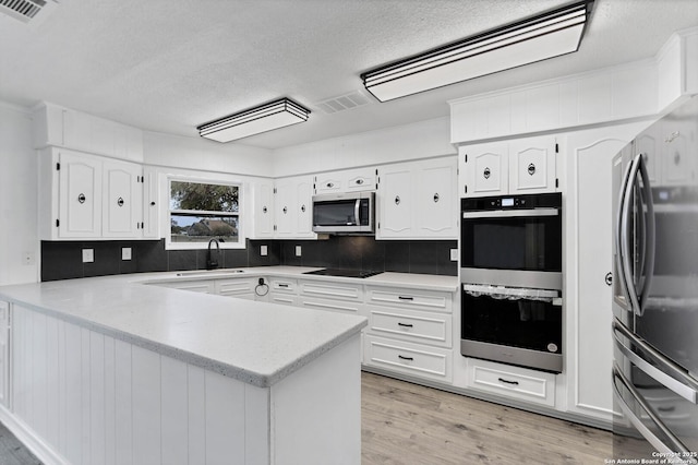 kitchen with appliances with stainless steel finishes, visible vents, a sink, and a peninsula