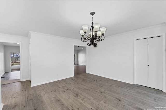 unfurnished dining area featuring ornamental molding, an inviting chandelier, baseboards, and wood finished floors