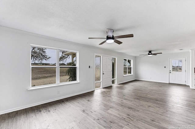 unfurnished living room featuring a textured ceiling, plenty of natural light, and wood finished floors