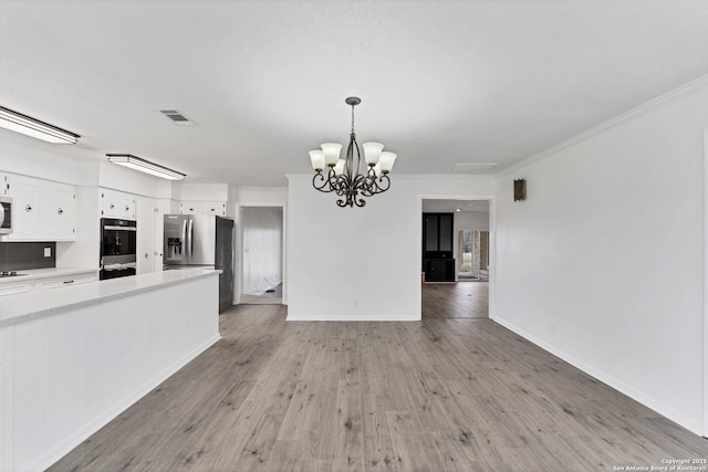 unfurnished living room featuring light wood-style floors, visible vents, crown molding, and a notable chandelier