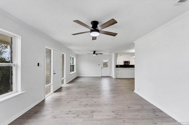 unfurnished living room with crown molding, visible vents, ceiling fan, wood finished floors, and baseboards