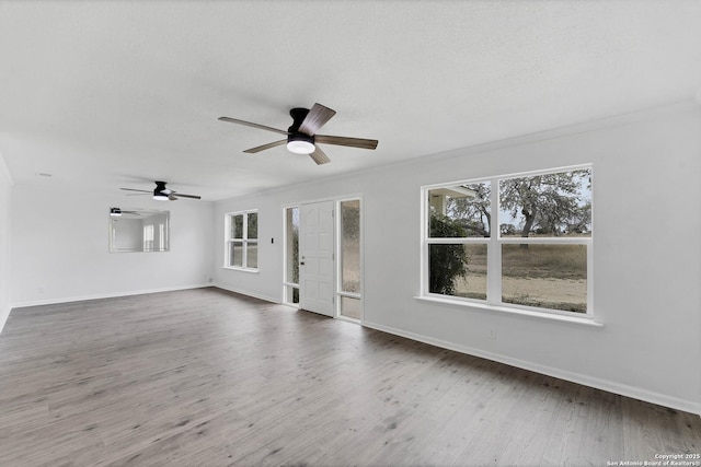 unfurnished living room featuring a textured ceiling, wood finished floors, a ceiling fan, and baseboards