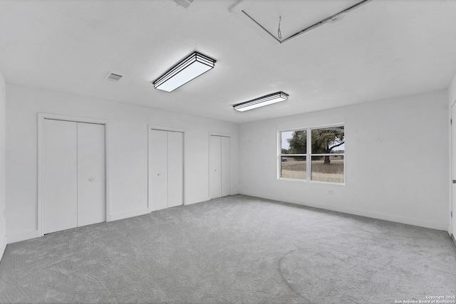 empty room featuring attic access, visible vents, and carpet floors