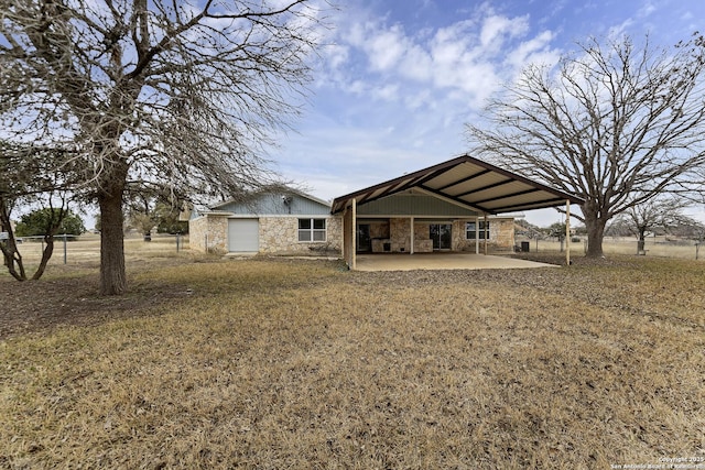 rear view of house with stone siding, a carport, and a patio