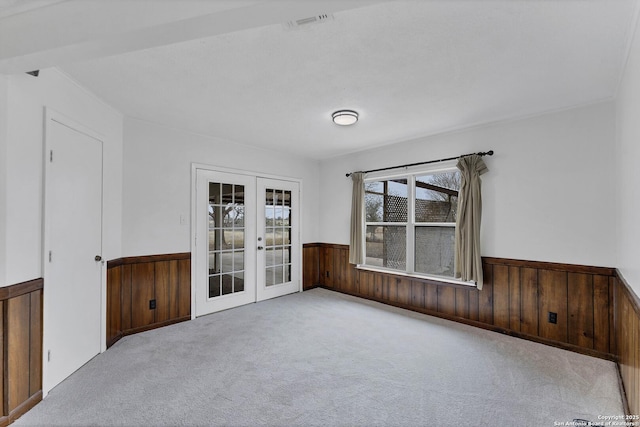 spare room with french doors, wainscoting, wooden walls, and carpet flooring