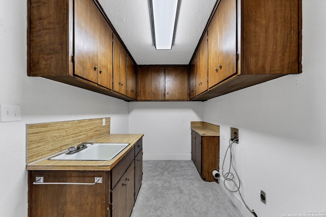 washroom with cabinet space, baseboards, light colored carpet, washer hookup, and a sink