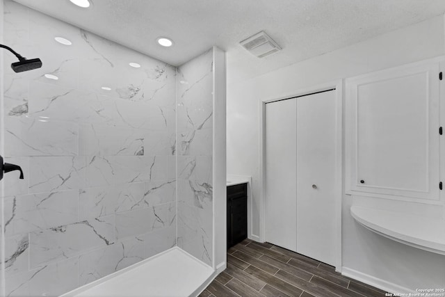 full bath featuring wood finish floors, visible vents, a tile shower, and recessed lighting