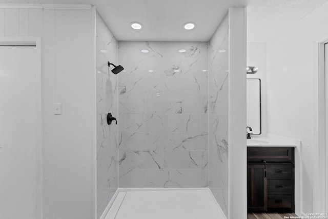 full bathroom featuring a textured ceiling, tiled shower, vanity, and recessed lighting