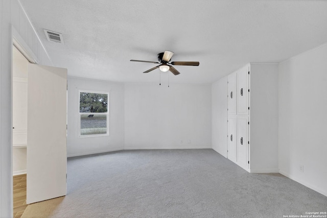 unfurnished room featuring light carpet, ceiling fan, a textured ceiling, and visible vents