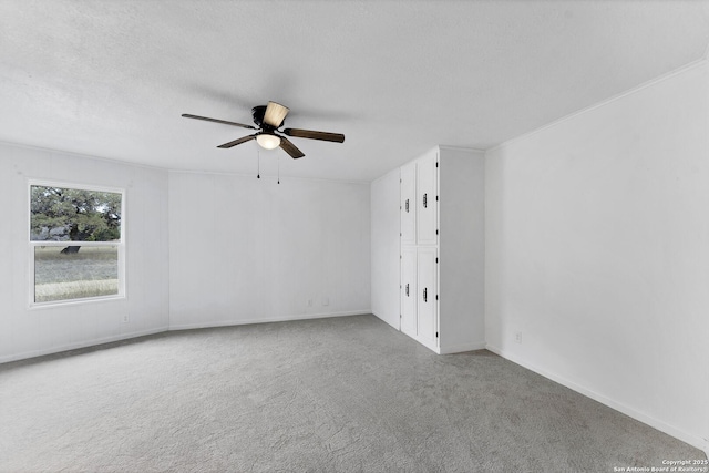 unfurnished room with ceiling fan, a textured ceiling, baseboards, and carpet flooring