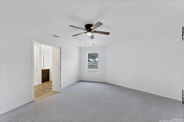 carpeted spare room with ceiling fan and visible vents