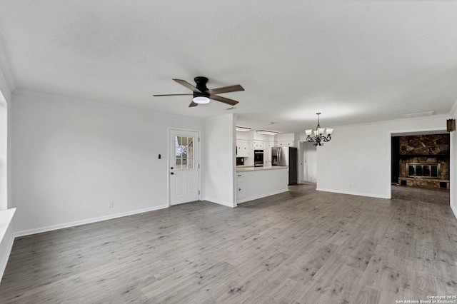 unfurnished living room with wood finished floors, visible vents, baseboards, and ceiling fan with notable chandelier