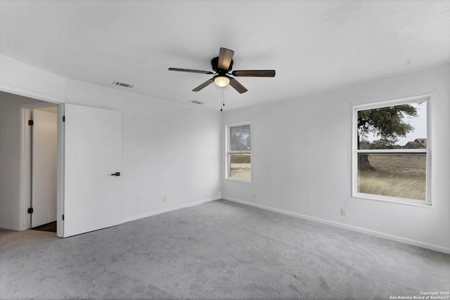 carpeted spare room with visible vents, ceiling fan, and baseboards