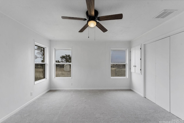 unfurnished bedroom with carpet, visible vents, ceiling fan, a textured ceiling, and baseboards