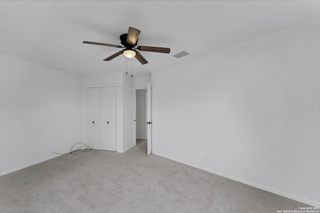 empty room featuring ceiling fan, carpet flooring, visible vents, and baseboards