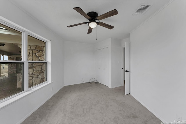 carpeted spare room featuring baseboards, visible vents, and a ceiling fan