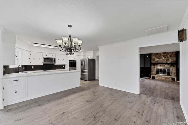 kitchen with a chandelier, stainless steel appliances, a fireplace, a sink, and open floor plan