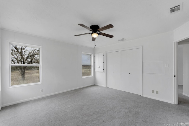 unfurnished bedroom featuring baseboards, visible vents, a ceiling fan, carpet, and a closet