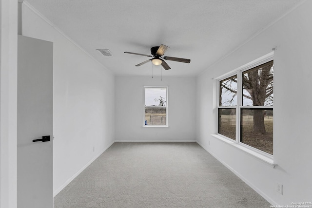 carpeted empty room featuring baseboards, visible vents, and ceiling fan