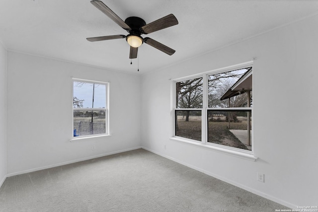 carpeted spare room featuring a ceiling fan and baseboards