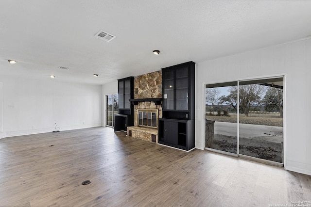 unfurnished living room with a fireplace, visible vents, and wood finished floors