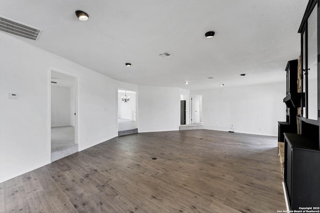 unfurnished living room featuring a chandelier, wood finished floors, and visible vents